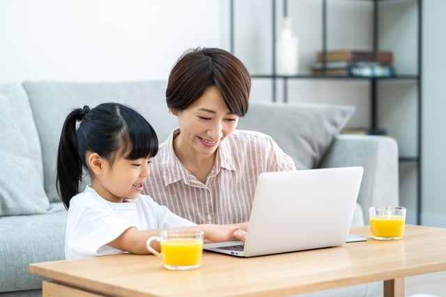 コロナ禍のニューノーマルで広がった<衣・食・住>のサービスとマーケティング視点での考察 リビングでノートPCを見ながら寛ぐ親子
